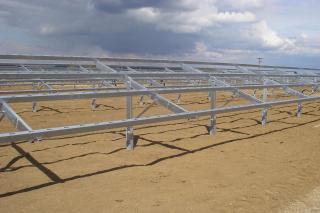 Structure métallique de montage au sol pour un grand parc solaire, avec ciel nuageux.